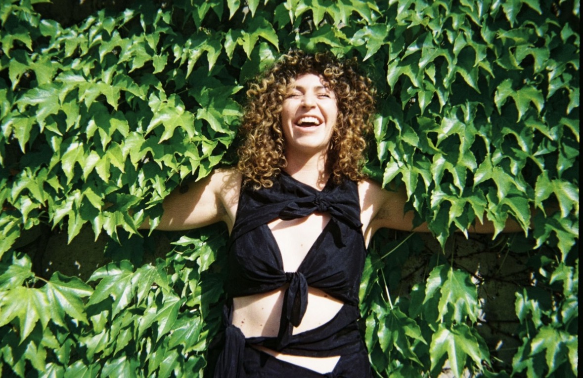 Kate Russell laughing in front of a wall of green ivy