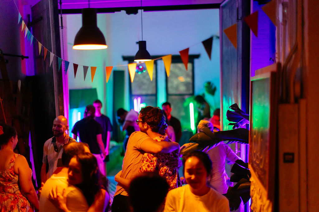Two people embracing in a neon-lit doorway as the room dances around them