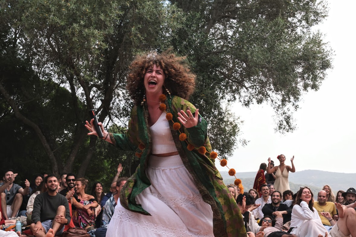Kate mid-performance on a hilltop, a seated crowd cheering around her